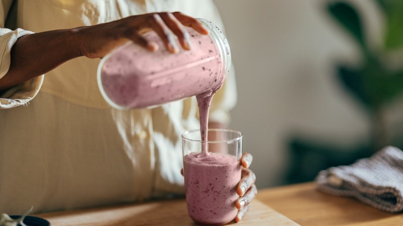 vrouw schenkt smoothie vanuit blender in glas
